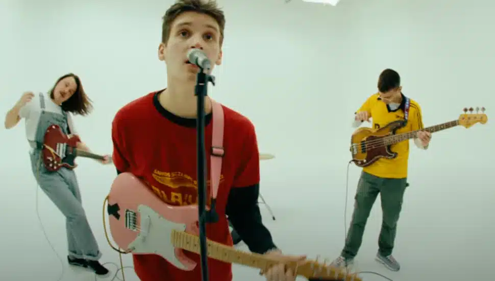 jsolomon playing guitar with two bandmates in music video