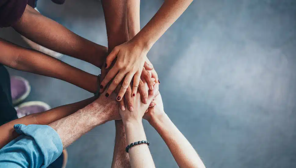 aerial view of several hands of various skin tones stacking on top of eachother