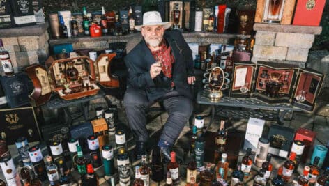 Mike Daley among a collection of whiskey bottles