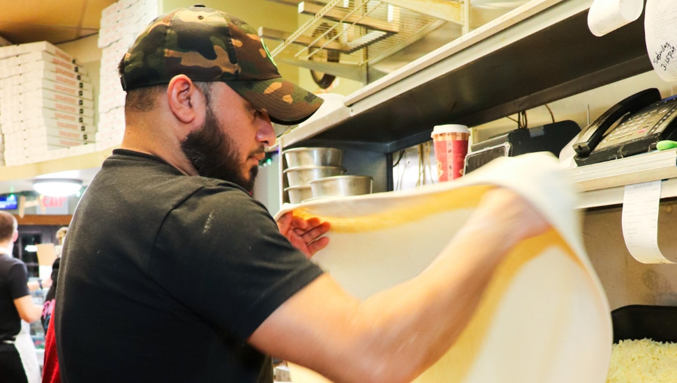 employee at The Valley Pizza flipping dough
