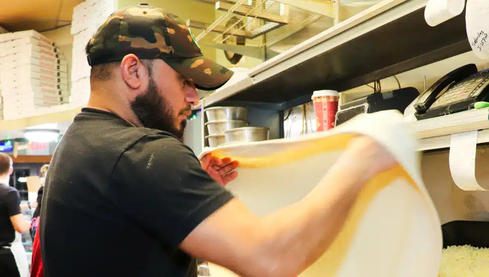 employee at The Valley Pizza flipping dough