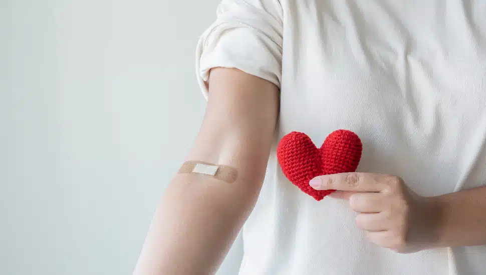 Woman arm with the bandage other hand holding crocheted heart