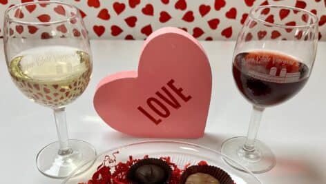 two glasses of wine, chocolate dish and heart