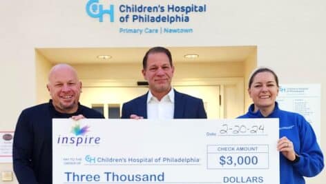 three people holding giant check at Children's Hospital of Philadelphia