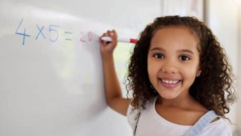young girl writing math equation white board