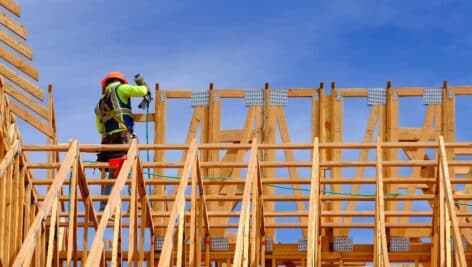 Construction workers working on new home or residential building with wooden beams framed and sky
