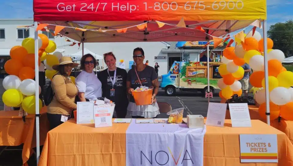 four NOVA Bucks staff members under tent at a table display