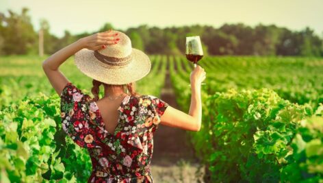 Woman raising a glass of wine in a vineyard