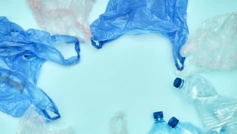 Plastic bags of used and bottles on blue background. Eco friendly concept. Copy space. Flat lay.