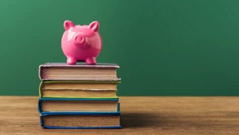 pink piggy bank on books, wooden table and green background