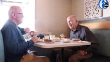 two men sitting at diner table eating breakfast