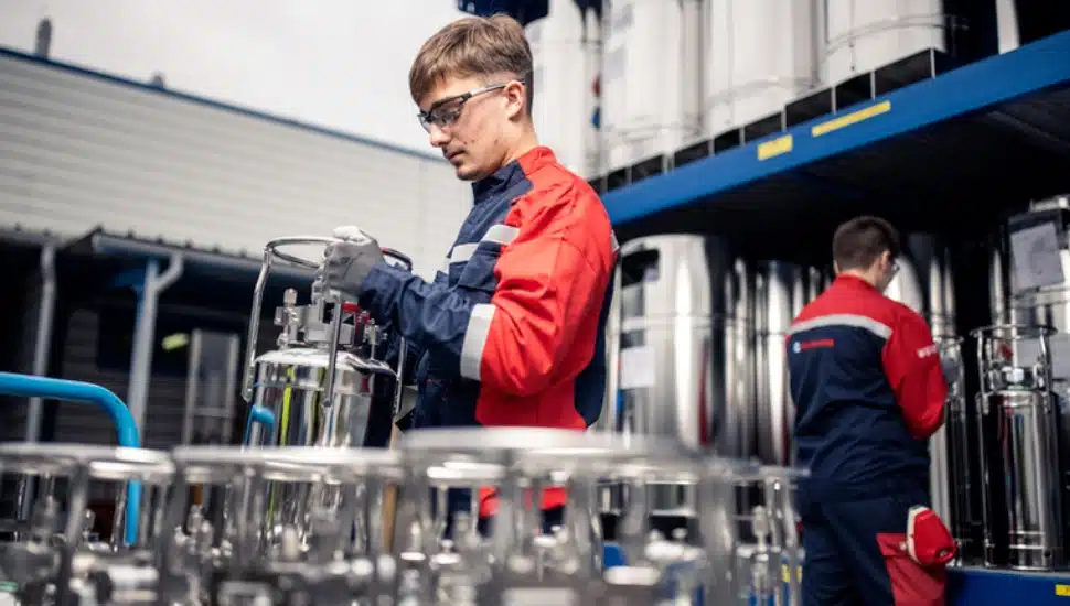 Person in Air Liquide factory with gas tanks wearing jumpsuit and goggles