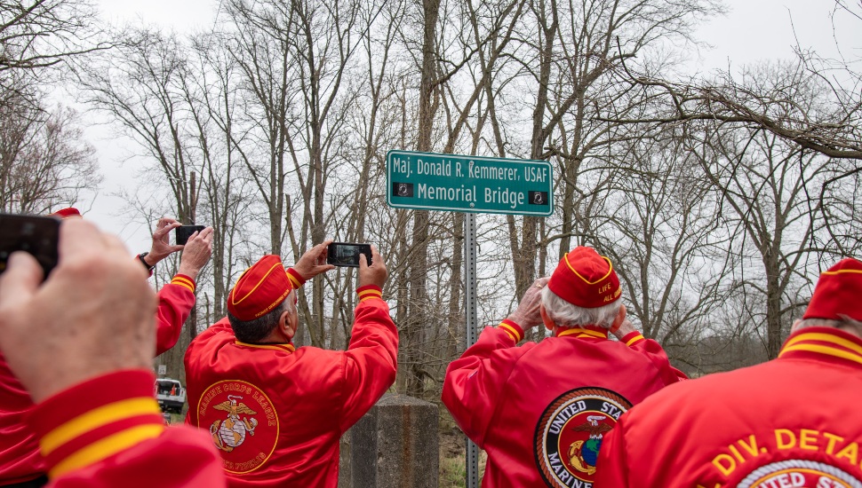 veterans in red jackets and berets taking photo of signage of Donald R. Kemmerer Memorial Bridge
