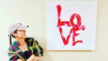 Artist and business owner Dori Desautel Broudy gazes up at her "Love" artwork on canvas.