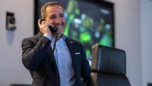 Howie Roseman smiles while speaking on the phone.