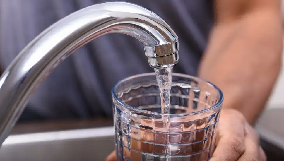 Hand with drinking glass filling water from kitchen faucet, home and lifestyle concept