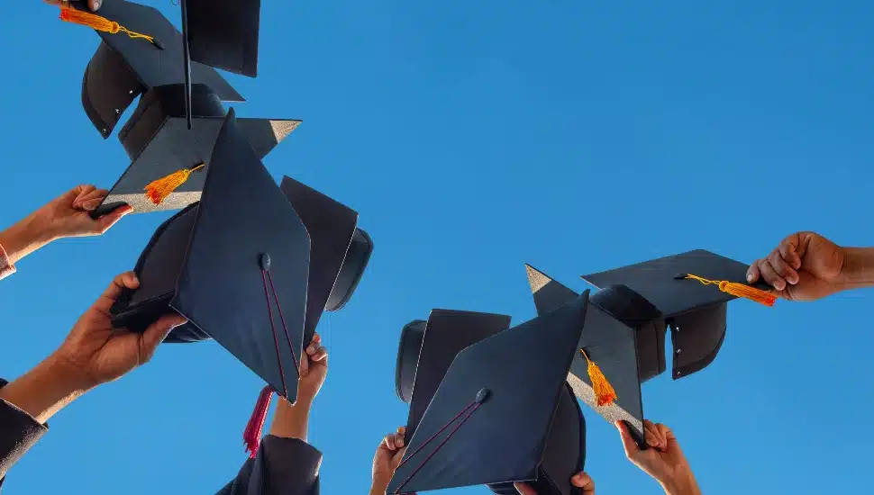 students holding graduation caps in the air