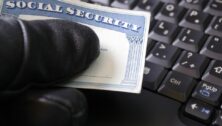 person holding Social Security card above keyboard.