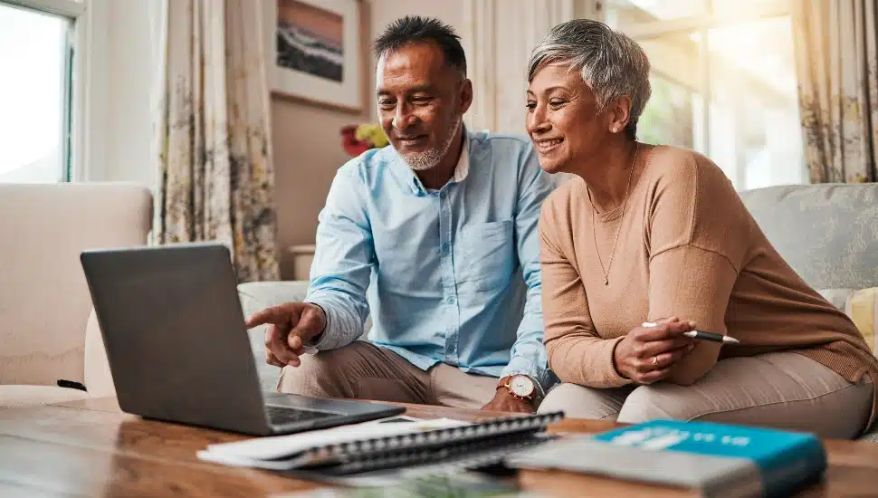Mature couple, sofa and laptop for planning finance, retirement funding and investment or asset management at home. Elderly people or man and woman reading information on computer for pension savings