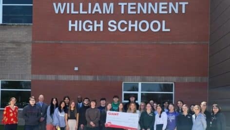 about a a few dozen high school students and staff with large check from giant in front of William Tennent High School.