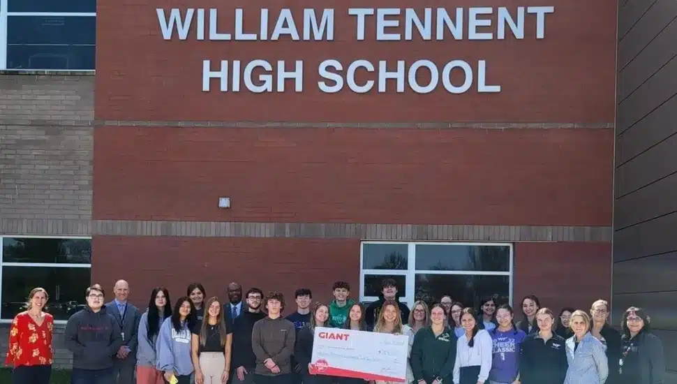 about a a few dozen high school students and staff with large check from giant in front of William Tennent High School.