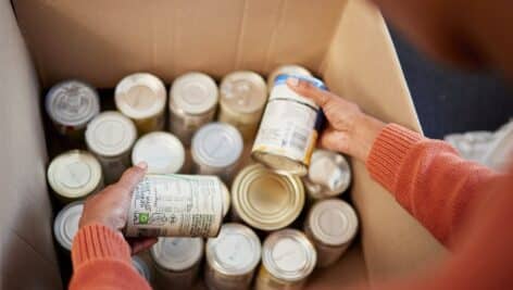 person putting cans into cardboard box