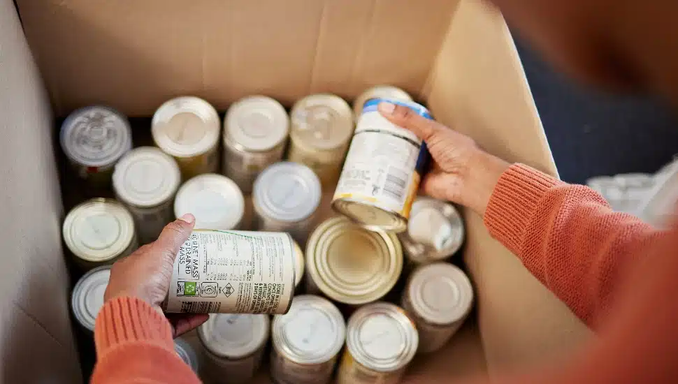 person putting cans into cardboard box
