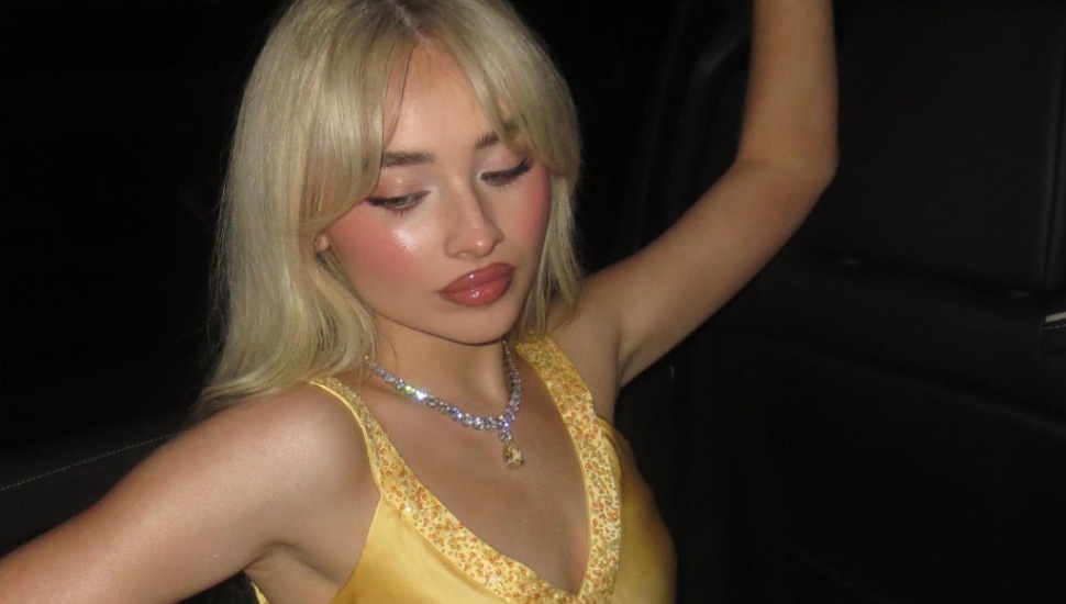 Sabrina Carpenter in a vehicle of sorts wearing yellow dress for birthday