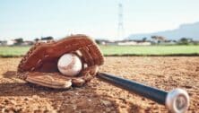 baseball glove with baseball and baseball bat on field