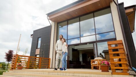 millionaire homeowners standing in front of their house.