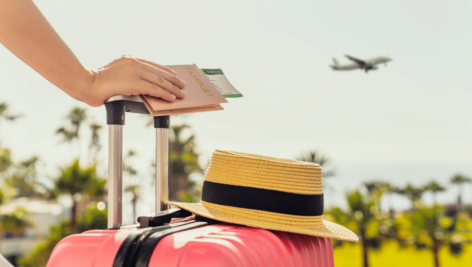 person with luggage and travel tickets looking at plane in sky