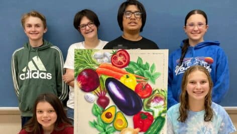 group of students posing with vegetable medley art