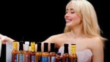 Sabrina Carpenter sitting at table with bottles of hot sauce