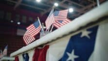 Elections in the United States of America. Close up of table for voting registration with American flags standing at polling place. Presidential race and election coverage. Civic duty and patriotism.