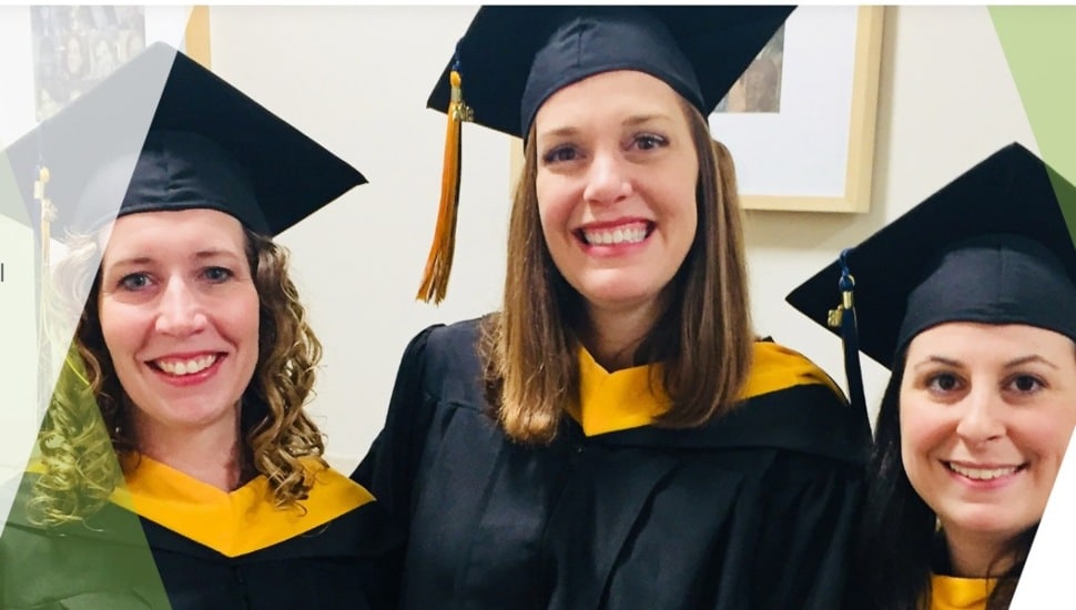 Three high school girls in graduation uniforms ready to graduate.