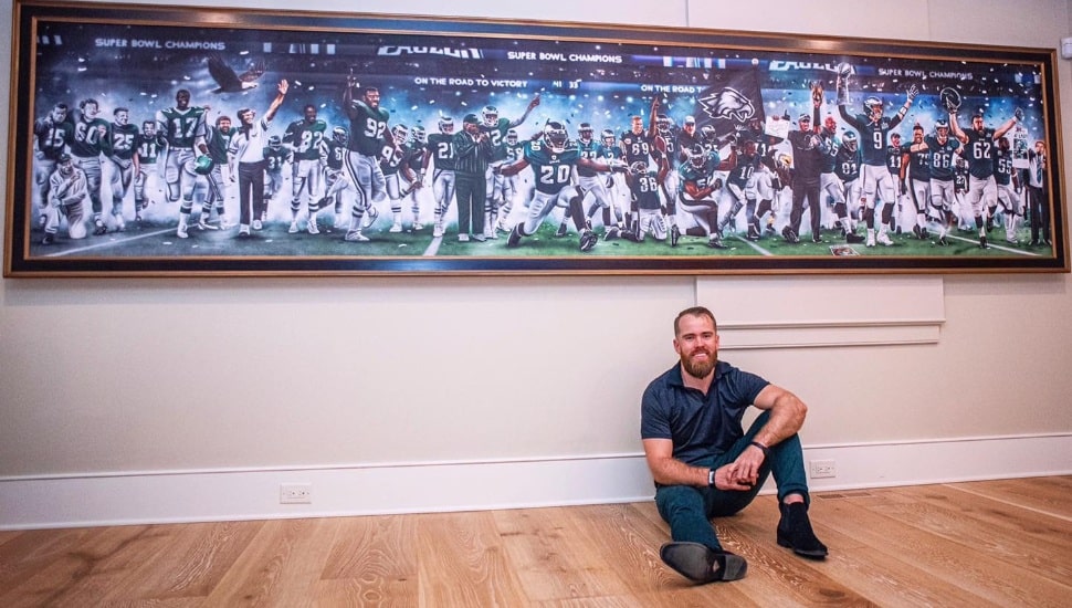 Jordan Spector sitting under large painting of The Eagles superbowl victory