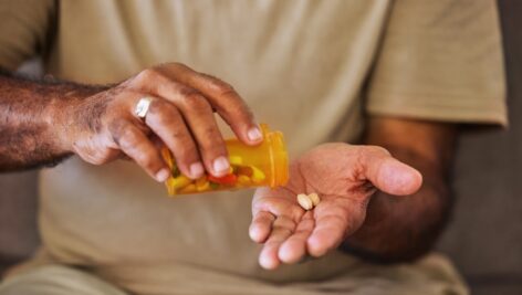 close up of hands and a pill bottle.