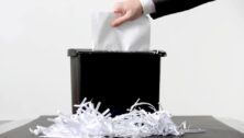 an arm outstretched placing paper in shredder.