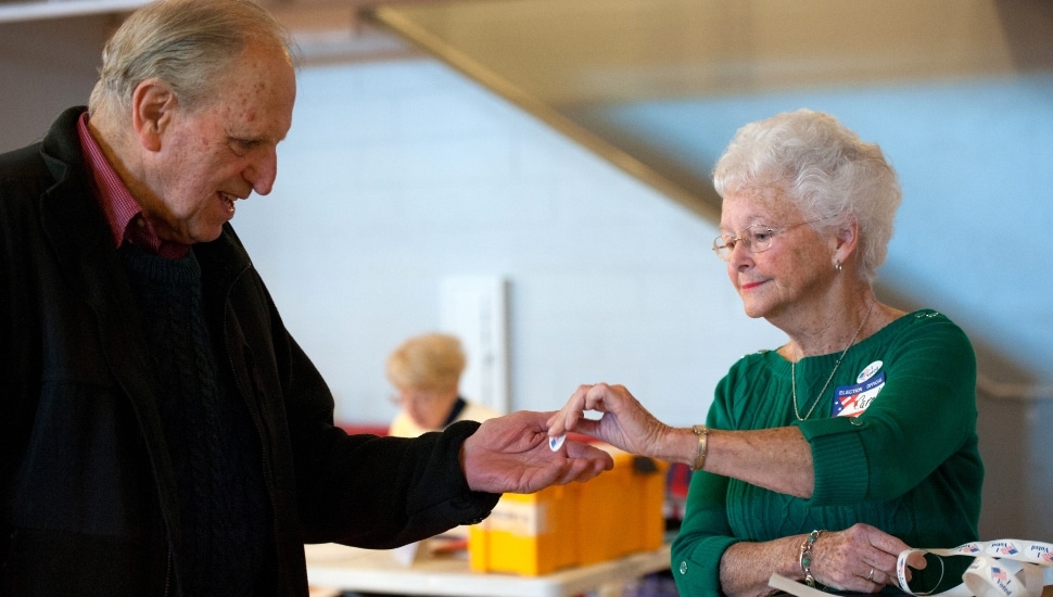 An older man after voting/receiving an "I voted" sticker.