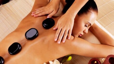 Adult woman having hot stone massage in spa salon.