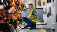 Female worker checking and controlling parts of robotic machine