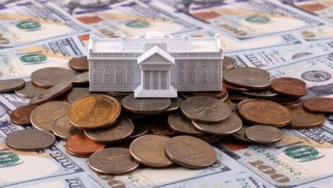 White House figurine atop a pile of money.