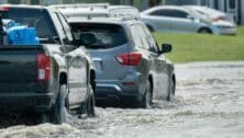 Cars navigate a flooded street.