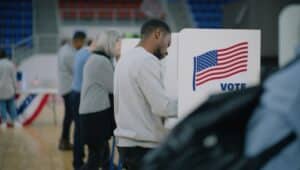 Male voter with bulletin in hands at a voting booth.