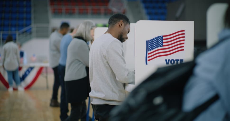 Male voter with bulletin in hands at a voting booth.