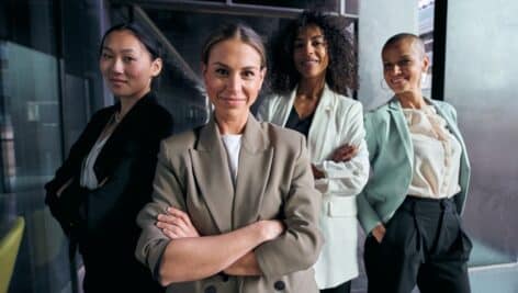 A group of women in suits with arms crossed.