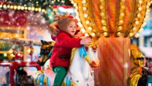 Kid at Xmas outdoor fair on winter day.