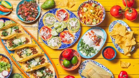 Table full of Mexican cuisine and plates.