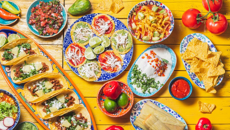 Table full of Mexican cuisine and plates.