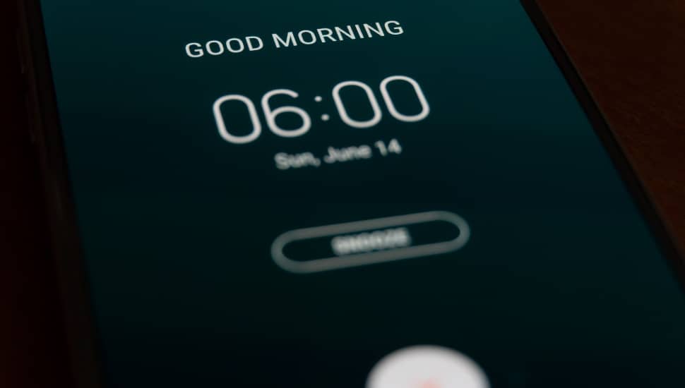 A smartphone alarm clock rings for 6 am